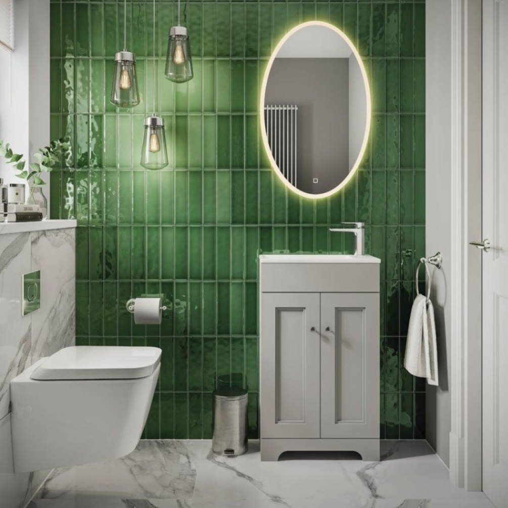 Product Lifestyle image of the HiB Arena 800mm Oval LED Bathroom Mirror mounted onto a wall with green tiles